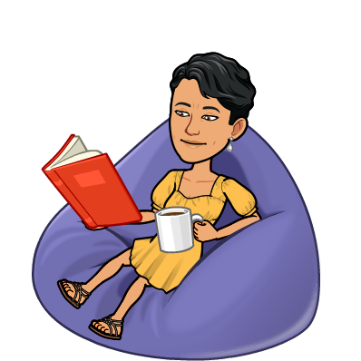 A person chilling on a bean bag chair while reading and drinking coffee.